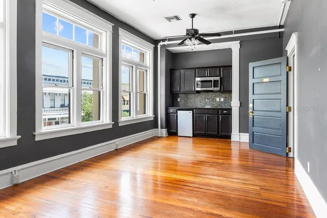 a view of an empty room with a kitchen and a window
