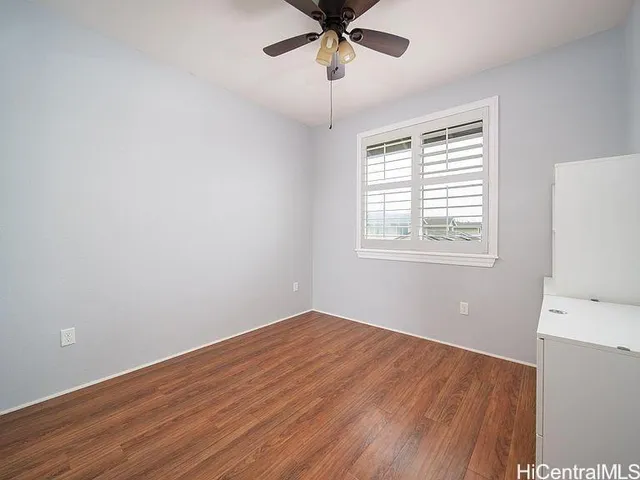 a view of empty room with wooden floor and fan
