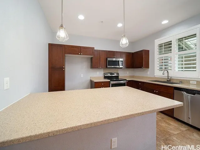 a kitchen with stainless steel appliances a refrigerator a sink a stove a microwave a center island and furniture