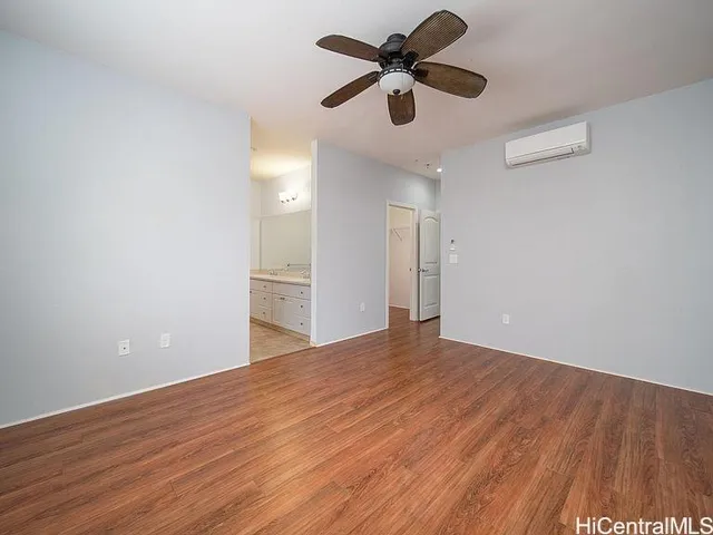 a view of an empty room with wooden floor and a ceiling fan
