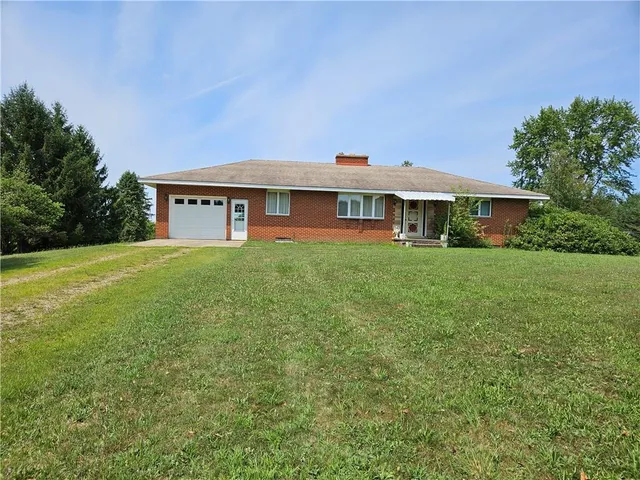 a view of a house with a big yard and large trees