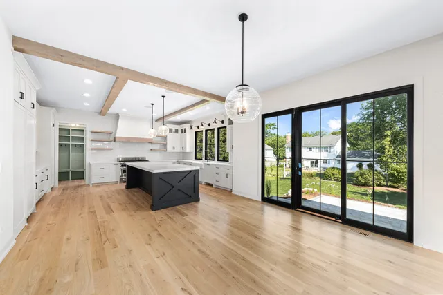 a large kitchen with stainless steel appliances kitchen island granite countertop a refrigerator a oven and a wooden floors