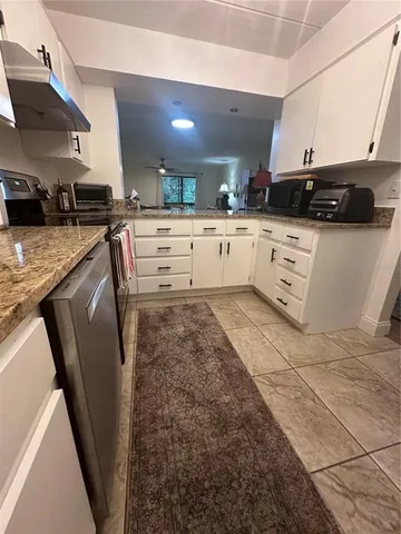 a kitchen with stainless steel appliances kitchen island granite countertop a sink a stove and cabinets