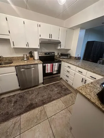 a kitchen with granite countertop a stove top oven sink and cabinets
