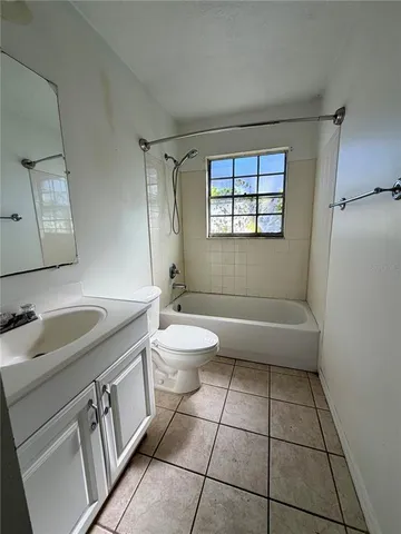 a bathroom with a granite countertop sink a toilet a mirror and bathtub
