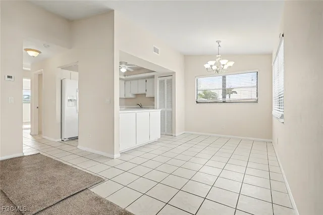 an empty room with kitchen view and wooden floor