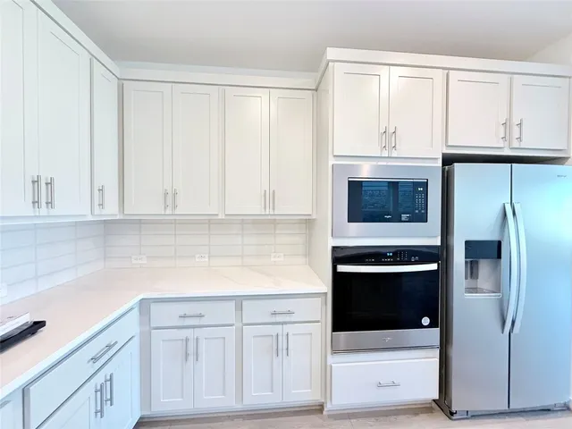 a kitchen with white cabinets and stainless steel appliances