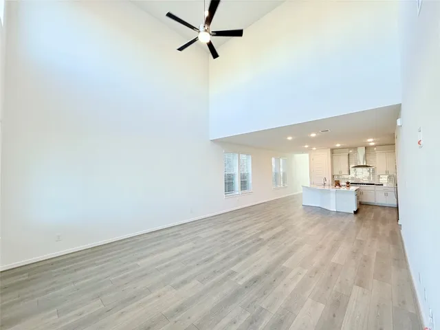 a view of a livingroom with a fireplace a ceiling fan and wooden floor