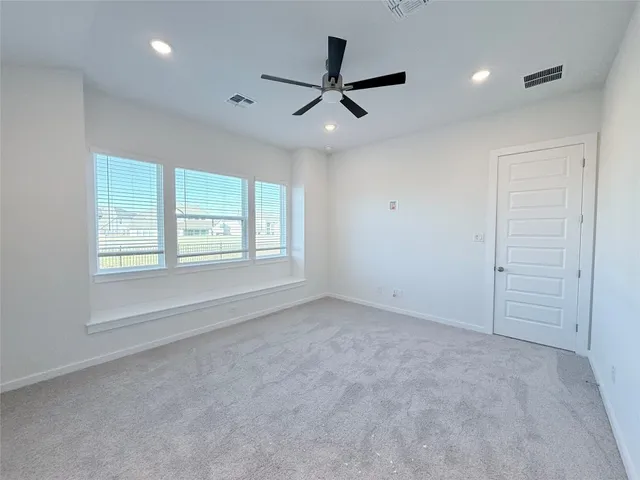 an empty room with ceiling fan and windows