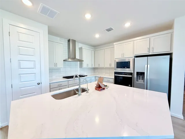 a kitchen with granite countertop a refrigerator oven a sink a stove and cabinets