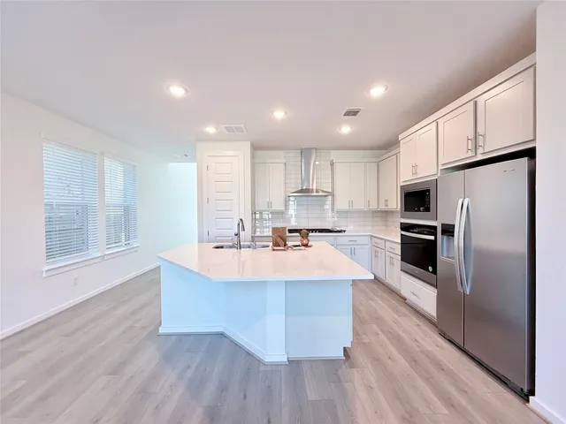 a large kitchen with stainless steel appliances kitchen island a large counter top and a refrigerator