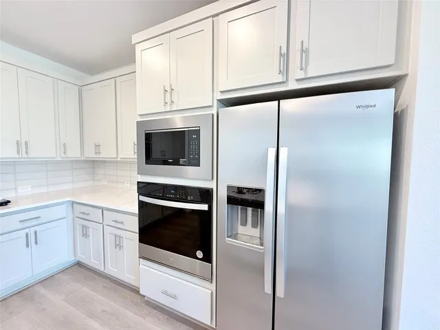 a kitchen with white cabinets and white appliances
