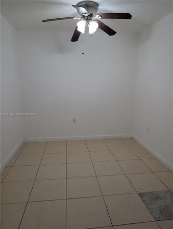 a view of an empty room with a chandelier fan