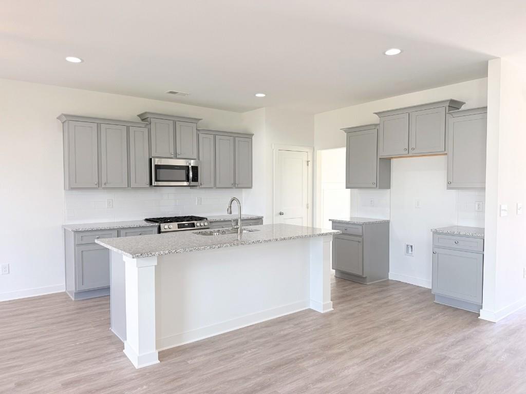 123 Purackal Lane Statham, GA 30666 - Photo 7 of 49 a kitchen with kitchen island a sink a stove a refrigerator and white cabinets