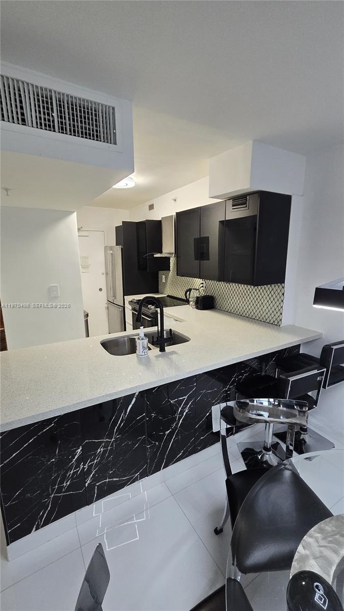 9195 Collins Avenue, Unit 406 Surfside, FL 33154 - Photo 3 of 12 a kitchen with a counter space a sink a stove and a refrigerator