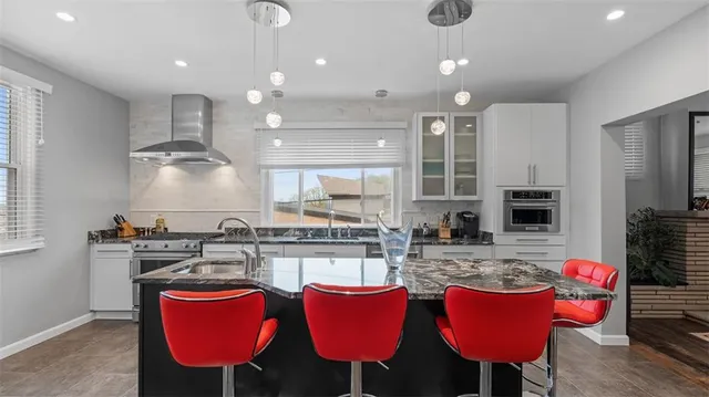 a kitchen with kitchen island granite countertop a sink cabinets and window