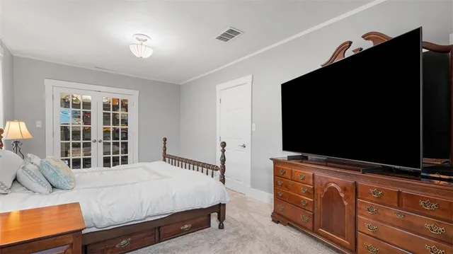 a bedroom with a bed and flat tv screen on dresser