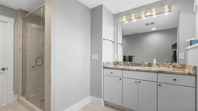 a bathroom with a granite countertop sink a mirror and a shower