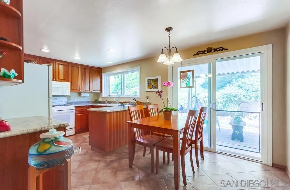 9140 Inverness Road Santee, CA 92071 - Photo 12 of 41 a dining room with stainless steel appliances granite countertop a stove a refrigerator a sink dishwasher a dining table and chairs with wooden floor