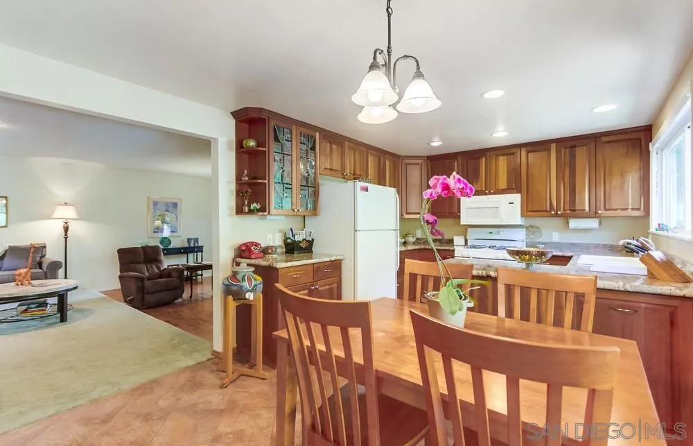 9140 Inverness Road Santee, CA 92071 - Photo 13 of 41 a kitchen with stainless steel appliances granite countertop a stove top oven a dining table and chairs with wooden floor