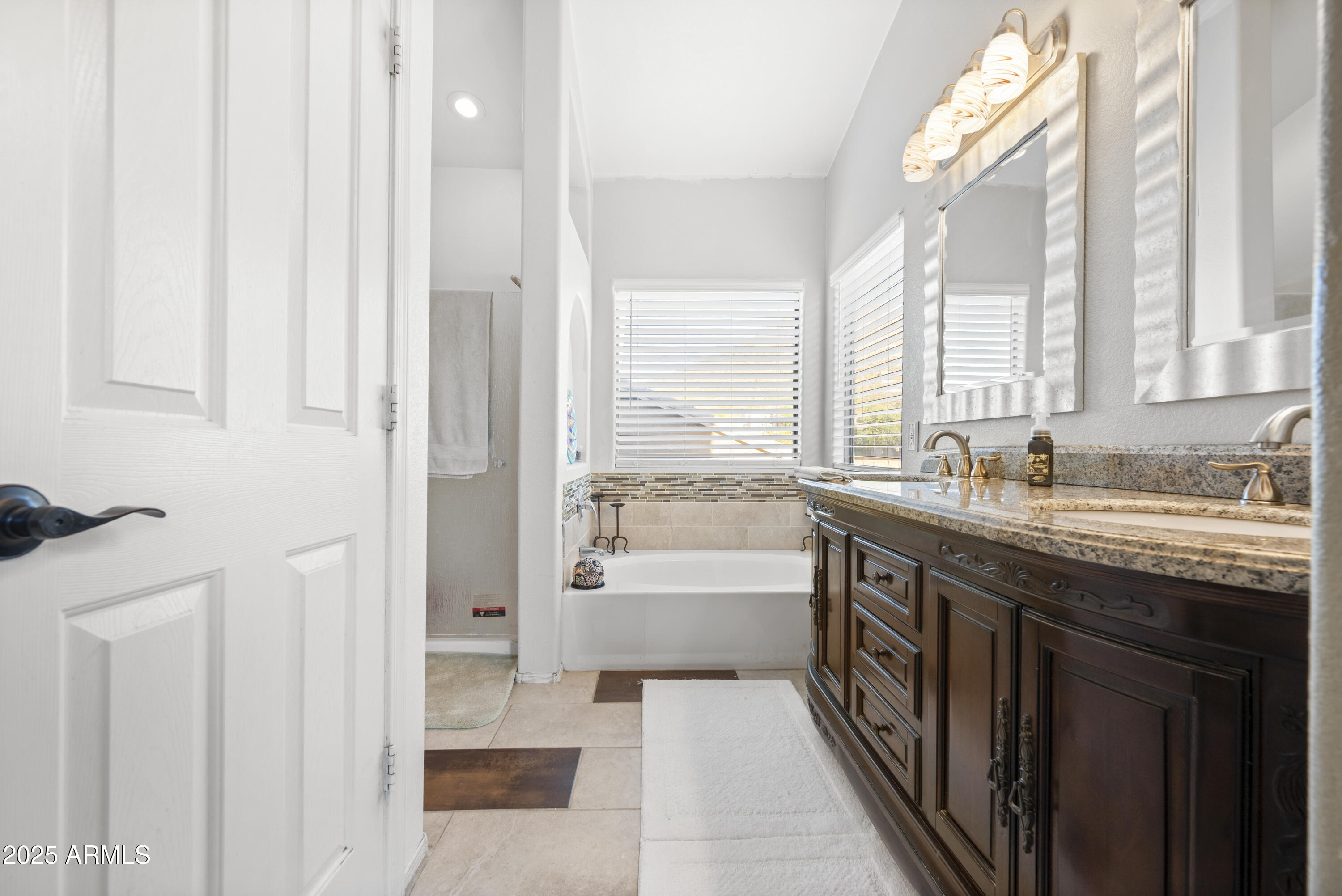 6419 West Briles Road Phoenix, AZ 85083 - Photo 18 of 28 a bathroom with a granite countertop sink a large mirror and a bathtub next to a window