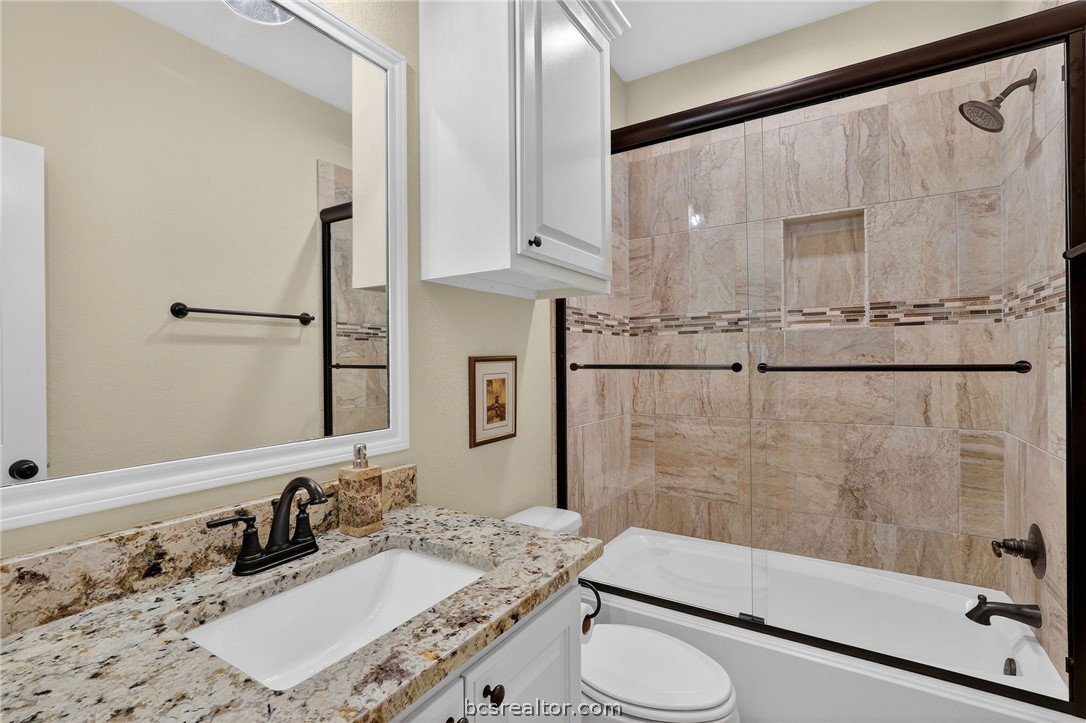 2004 Lexi Lane Bryan, TX 77807 - Photo 17 of 47 a bathroom with a granite countertop sink a mirror and shower