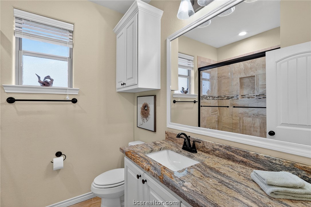 2004 Lexi Lane Bryan, TX 77807 - Photo 34 of 47 a bathroom with a granite countertop sink mirror vanity and toilet