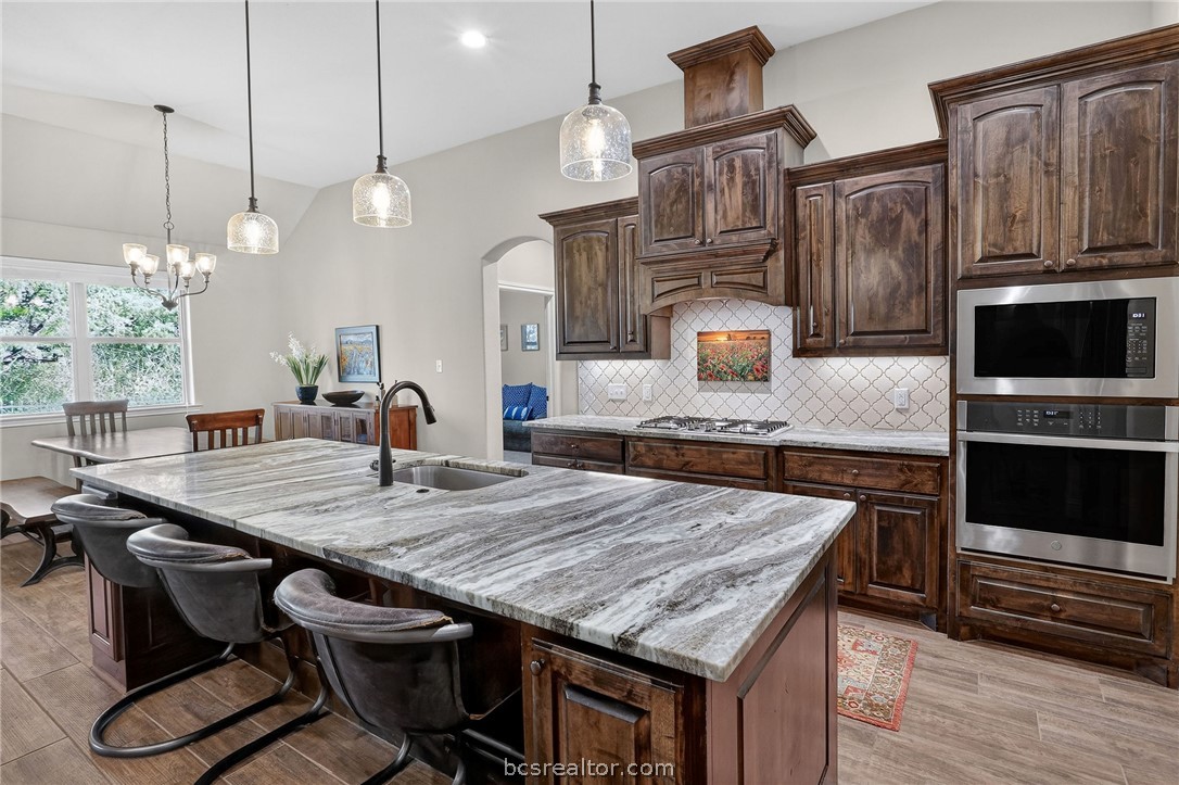 2004 Lexi Lane Bryan, TX 77807 - Photo 8 of 47 a kitchen with granite countertop a table chairs stainless steel appliances and wooden floor