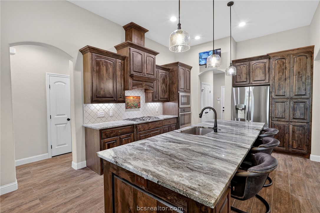 2004 Lexi Lane Bryan, TX 77807 - Photo 9 of 47 a kitchen with granite countertop a table chairs stainless steel appliances and wooden floor
