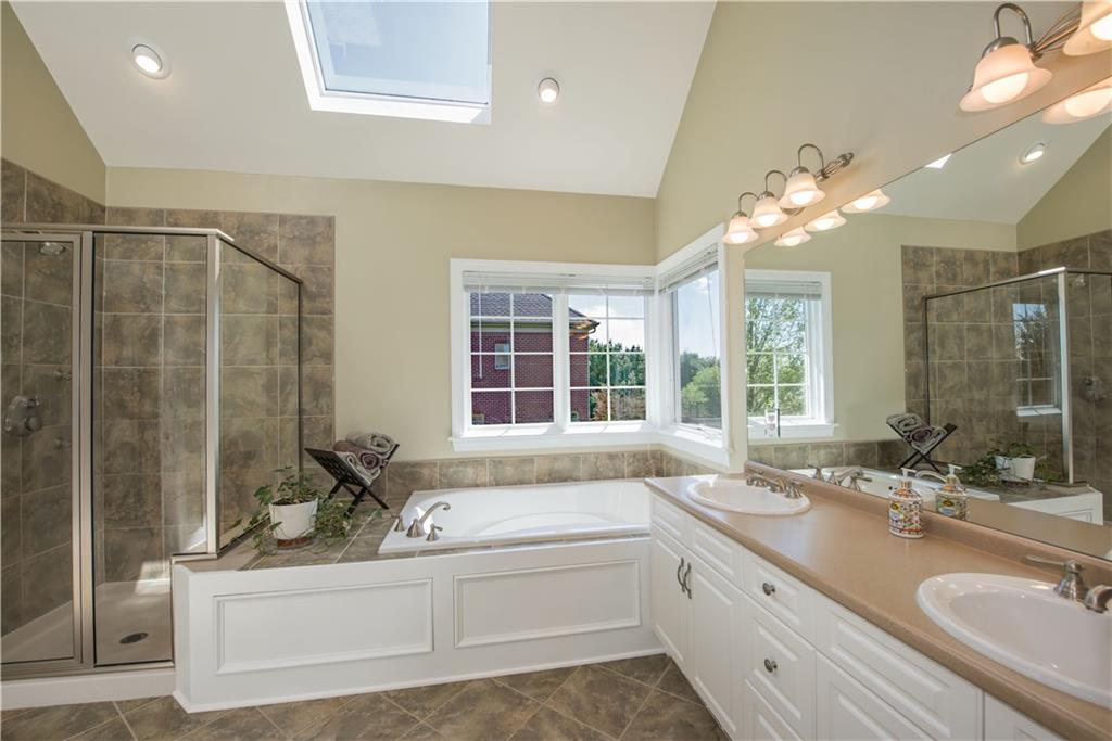 2019 Condor Lane Gibsonia, PA 15044 - Photo 23 of 39 a bathroom with a granite countertop sink a large mirror and a bathtub next to a window