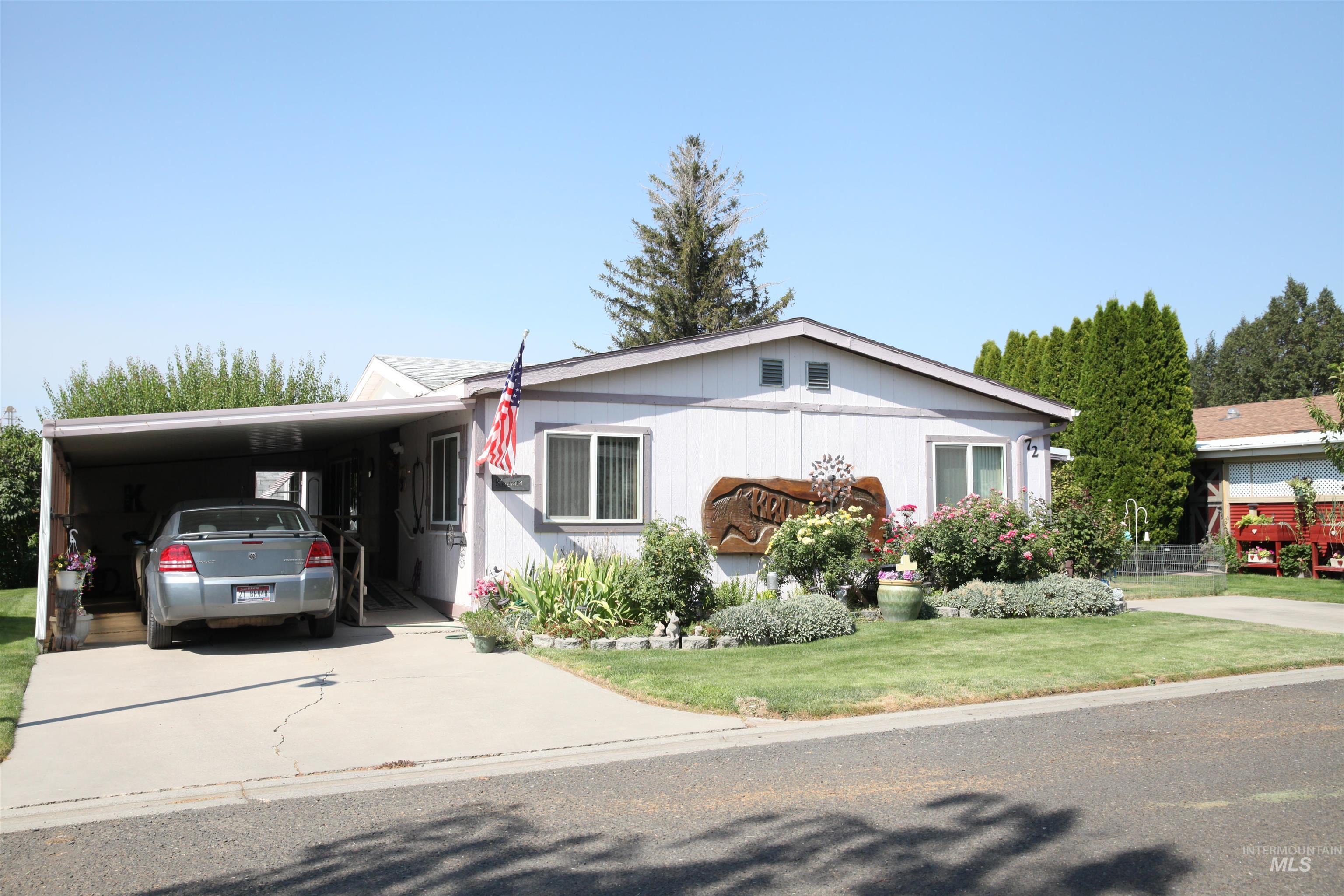 Front exterior featuring a carport, concrete driveway, and a landscaped garden