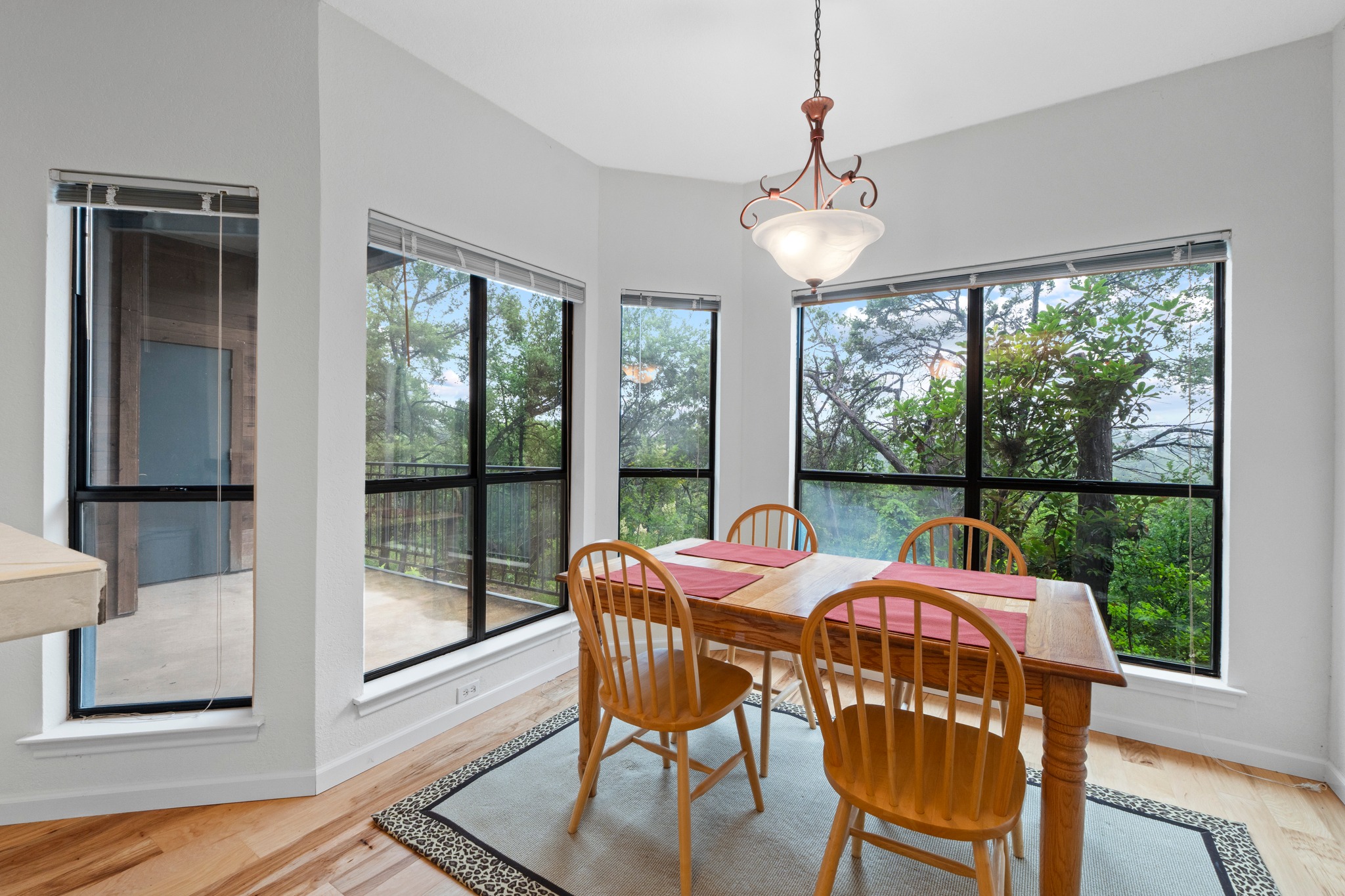 4711 Spicewood Springs Road, Unit 8146 Austin, TX 78759 - Photo 16 of 17 Dedicated dining space featuring expansive windows, wood-finish flooring, a contemporary chandelier, and a bay window design