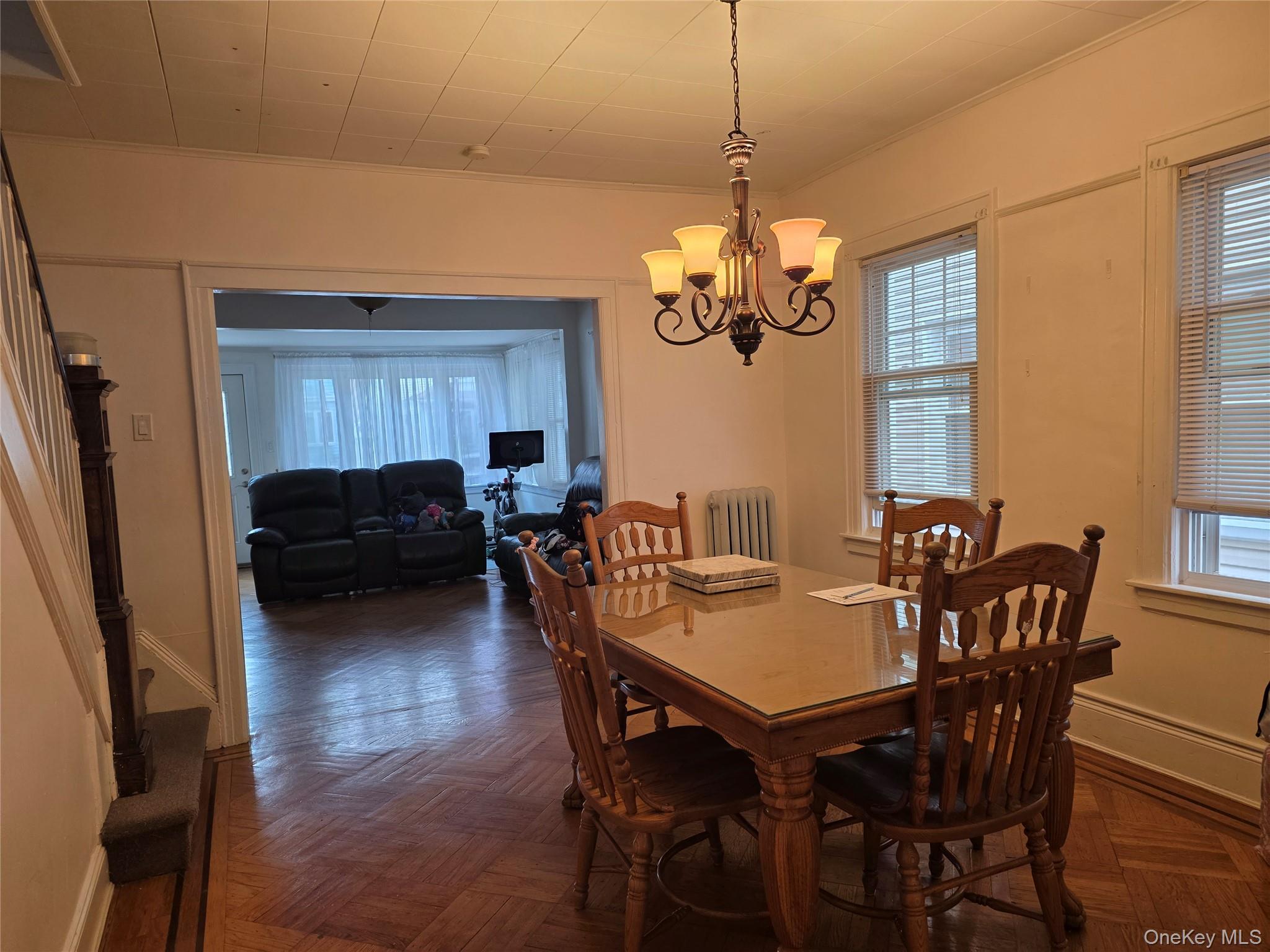 79-49 77th Road Queens, NY 11385 - Photo 3 of 12 Dining space featuring crown molding, stairs, radiator heating unit, and a chandelier