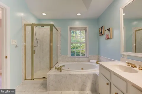 a spacious bathroom with a tub sink and mirror