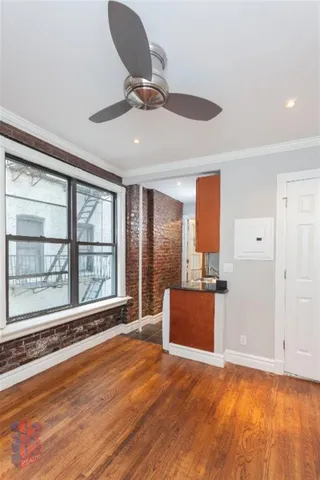 a view of an empty room with a window and wooden floor