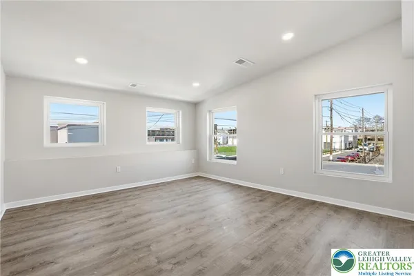 a view of an empty room with window and wooden floor
