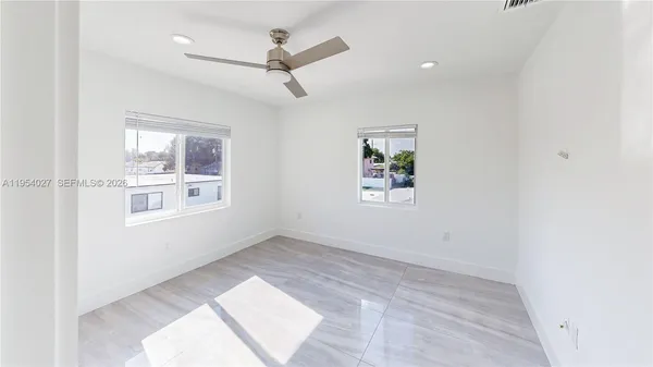 an empty room with windows and fan