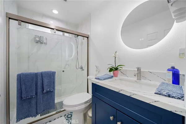a bathroom with a granite countertop shower a toilet and a sink