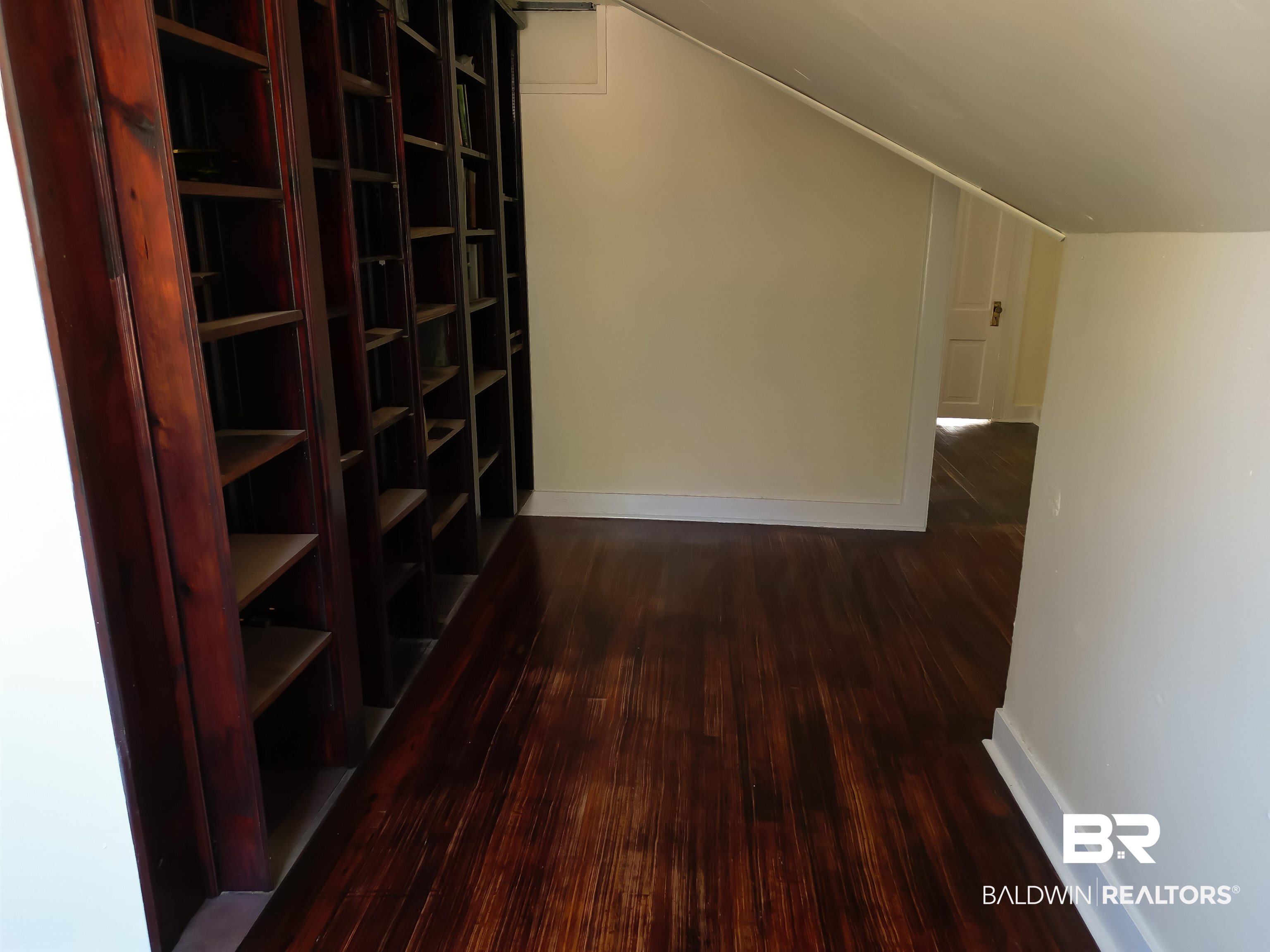 73 Liberty Street Monroeville, AL 36460 - Photo 16 of 29 Hallway featuring dark wood-type flooring and book shelf and vaulted ceiling