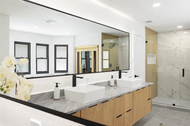 a bathroom with double vanity sinks and a shower