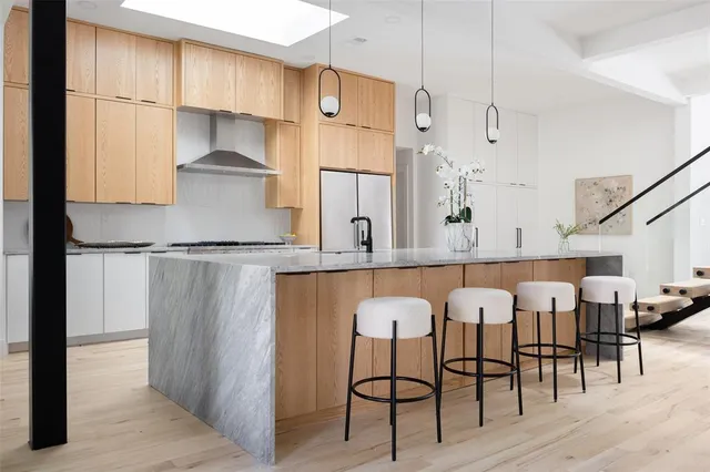 a kitchen with stainless steel appliances kitchen island granite countertop a table chairs in it and wooden floors