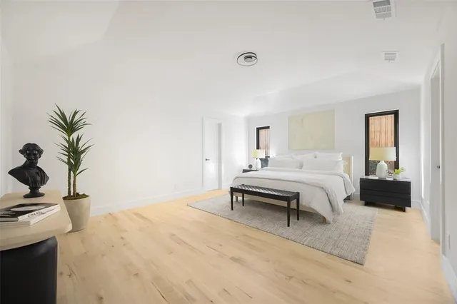 a bedroom with a large bed and a potted plant