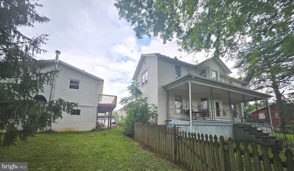 a view of house with a yard and a large tree