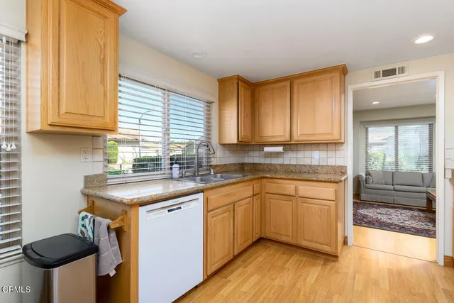 a kitchen with stainless steel appliances granite countertop a sink a stove cabinets and wooden floor