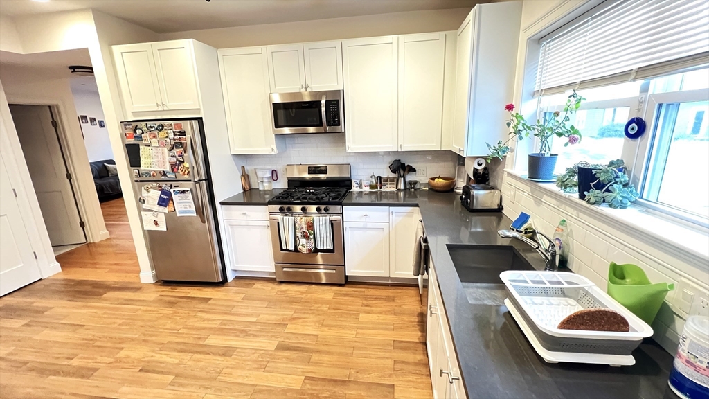 489 Main Street, Unit A Stoneham, MA 02180 - Photo 1 of 19 a kitchen with stainless steel appliances kitchen island granite countertop a refrigerator a stove top oven a sink dishwasher and white cabinets next to a window