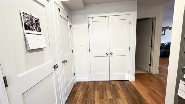 a view of a hallway with wooden floor and closet