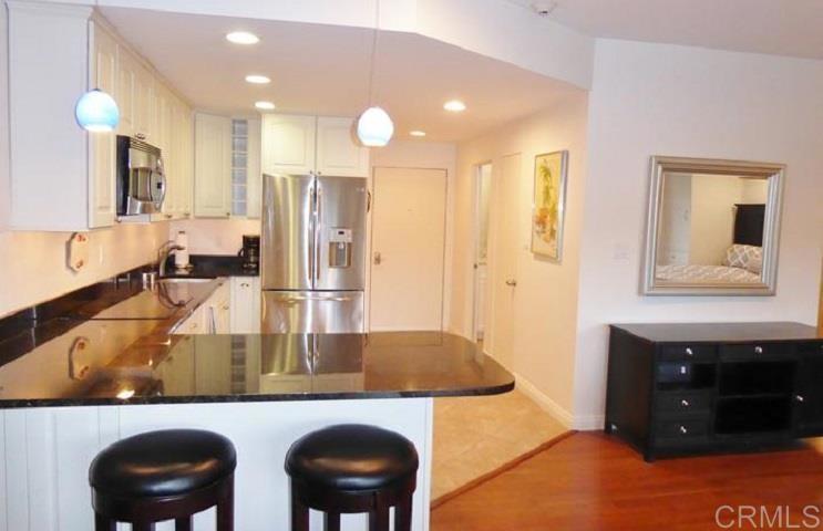 2005 Costa Del Mar Road, Unit 624 Carlsbad, CA 92009 - Photo 14 of 24 a kitchen with a table chairs and a refrigerator