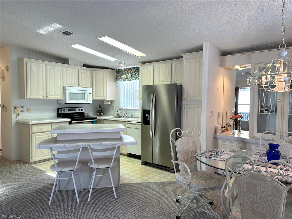 4680 Slash Pine Way West Estero, FL 33928 - Photo 8 of 20 a kitchen with refrigerator and chairs