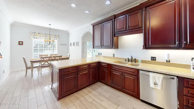 a kitchen with stainless steel appliances granite countertop wooden cabinets a sink and dishwasher a stove with wooden floors