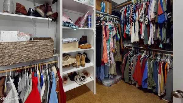a view of walk in closet with clothes and shoes